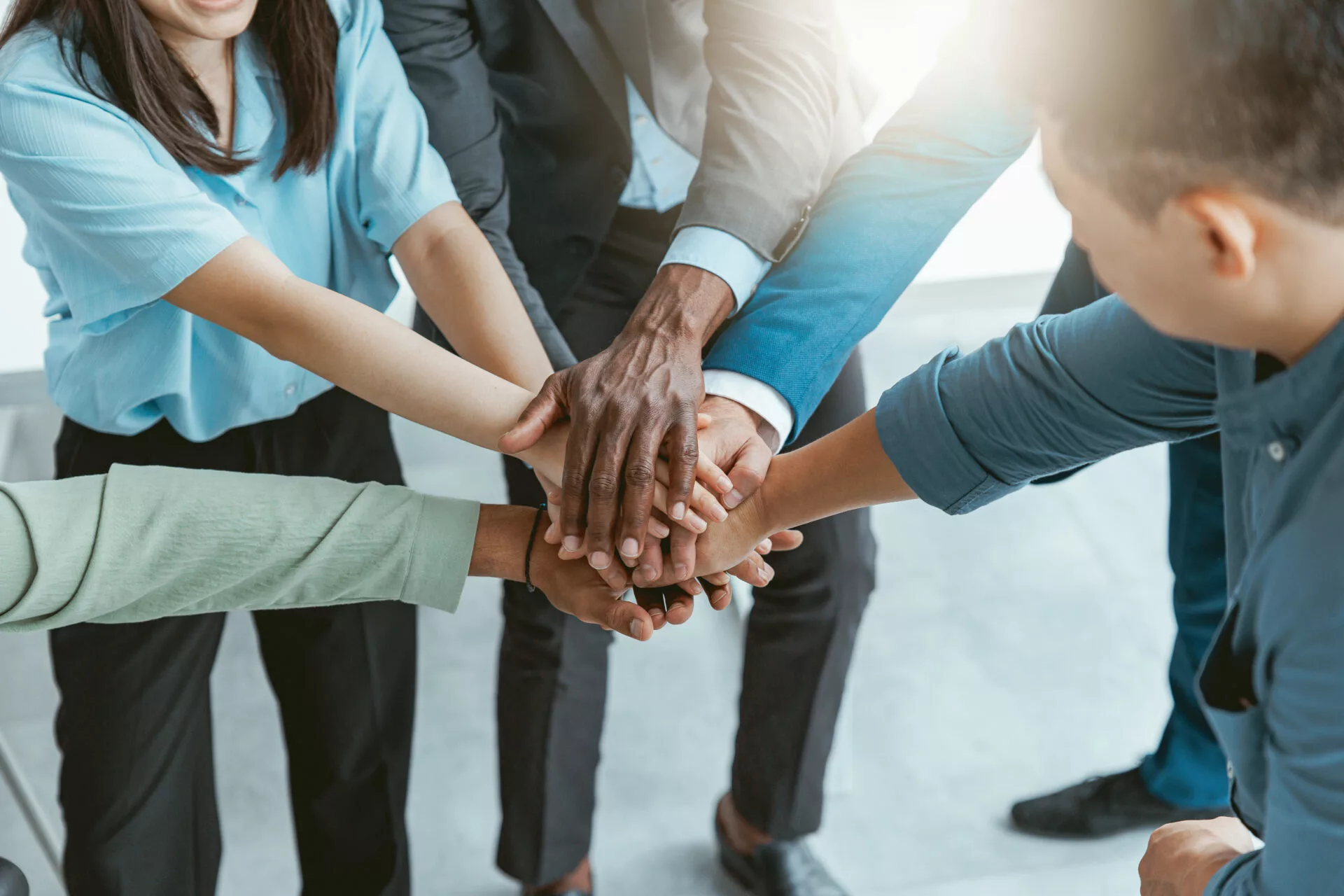 Teammitglieder legen ihre Hände übereinander als Symbol für Zusammenarbeit, Vertrauen und Positive Leadership.
